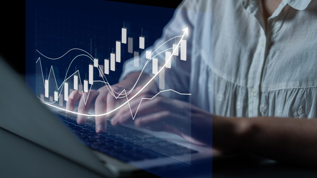 Close-up of a financial professional typing on a laptop with a digital holographic overlay showing growth charts and cash flow data.